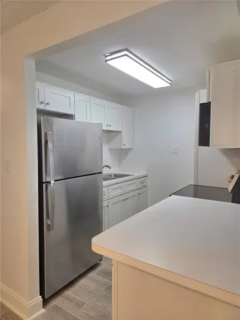 a kitchen with a refrigerator a stove top oven and cabinets