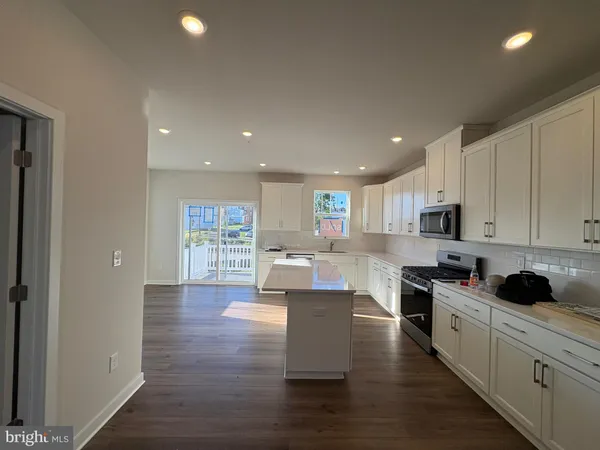 a kitchen with granite countertop a stove top oven a sink a counter space and cabinets