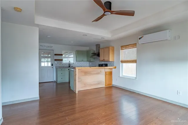a kitchen with stainless steel appliances kitchen island wooden floors and white walls