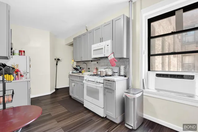 a kitchen with a stove and white cabinets with wooden floor