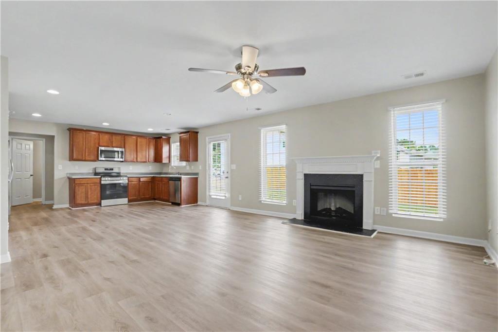 375 Walton View Fairburn, GA 30213 - Photo 12 of 38 a view of a livingroom with a fireplace a ceiling fan a kitchen a refrigerator and a fireplace