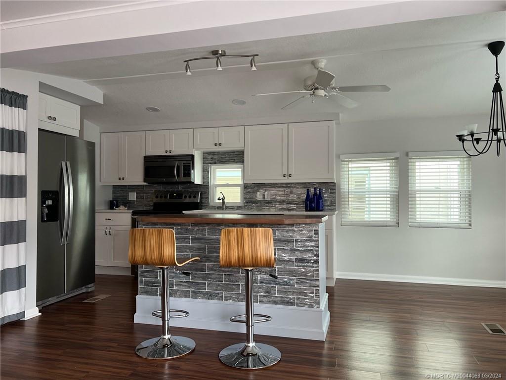 a kitchen with stainless steel appliances granite countertop a refrigerator a stove top oven and wooden floors