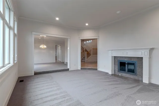 an empty room with wooden floor fireplace and windows