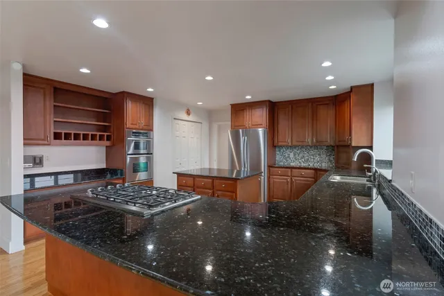 a kitchen with stainless steel appliances granite countertop a sink a stove and a refrigerator