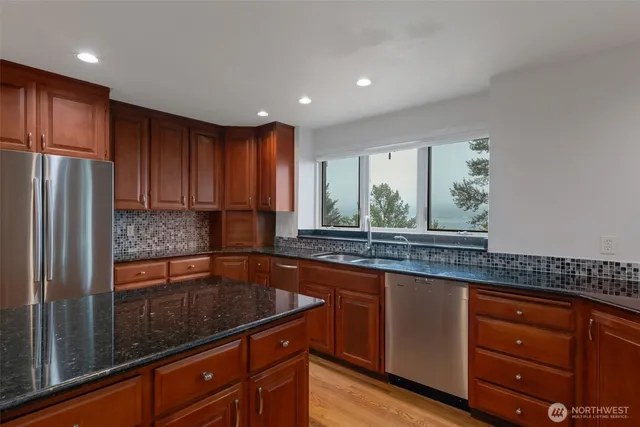 a kitchen with granite countertop wooden cabinets a sink and stainless steel appliances