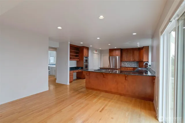 a view of kitchen with kitchen island wooden floor center island and stainless steel appliances