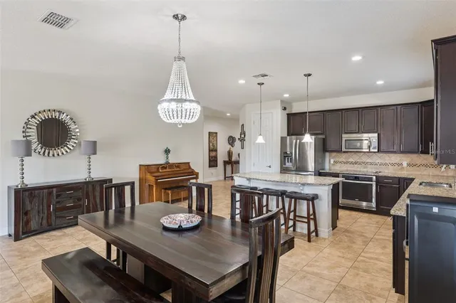 a kitchen with stainless steel appliances granite countertop a stove a refrigerator a kitchen island a dining table and chairs