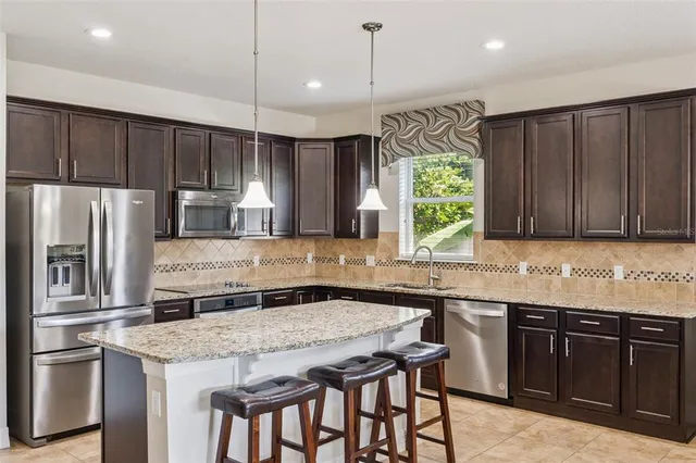 a kitchen with stainless steel appliances granite countertop wooden cabinets a refrigerator a sink and a stove