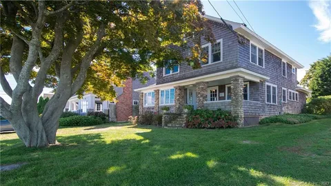 a view of a yard in front of a brick house with a large tree