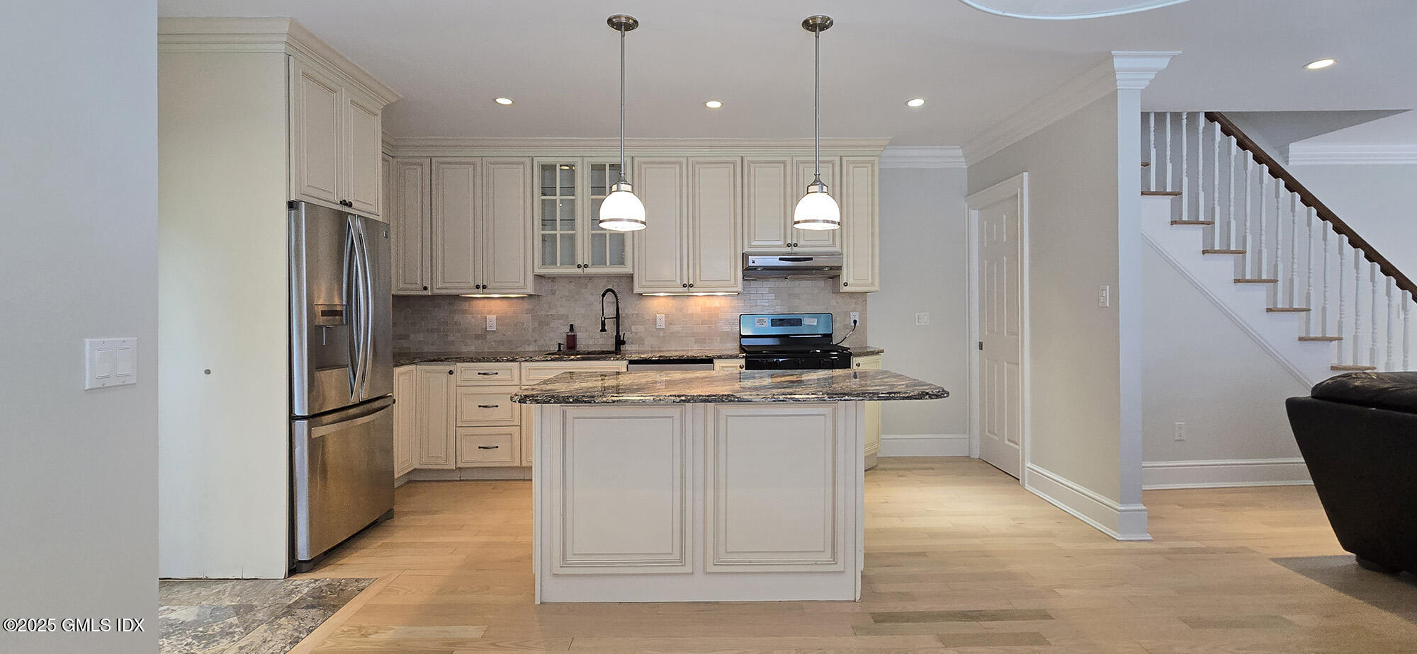 a kitchen with stainless steel appliances granite countertop a refrigerator a sink a stove and a wooden floors