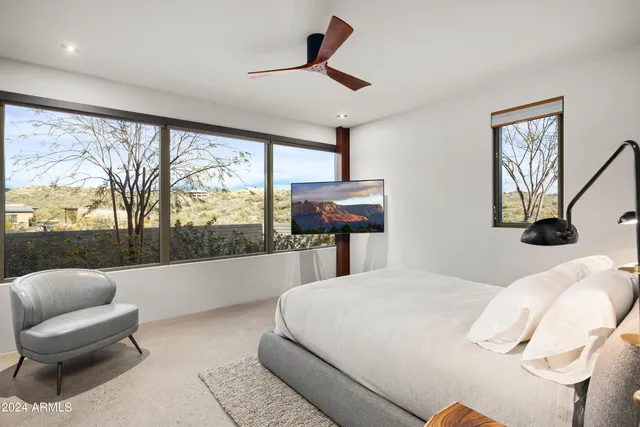 a bedroom with a bed a lamp on the wall and a flat screen tv