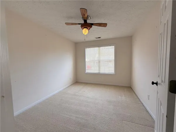 an empty room with windows and ceiling fan