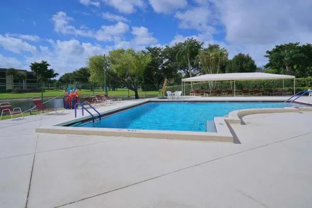 a view of swimming pool with seating space and trees in the background