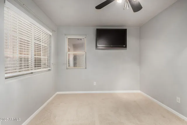 en empty room with windows and ceiling fan