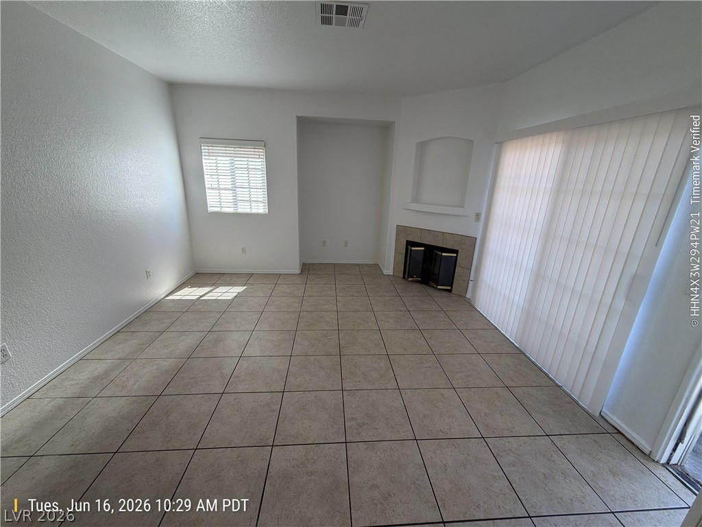 4730 East Craig Road, Unit 1124 Las Vegas, NV 89115 - Photo 3 of 22 A cozy living space features tiled flooring and a corner fireplace, offering comfort and style.