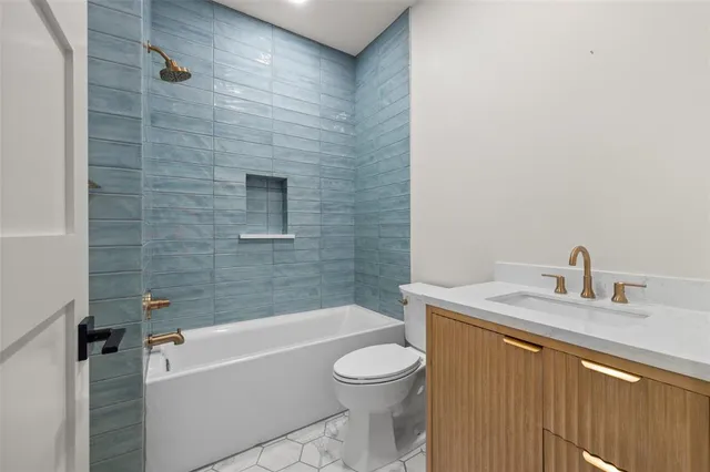 a bathroom with a granite countertop bathtub shower sink vanity and toilet