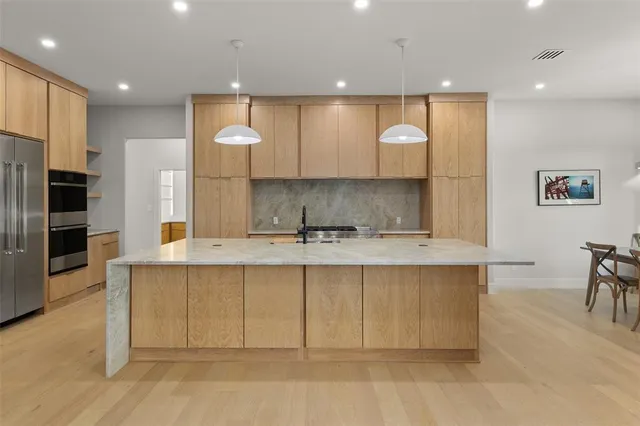 a view of a kitchen with kitchen island a sink stainless steel appliances and cabinets