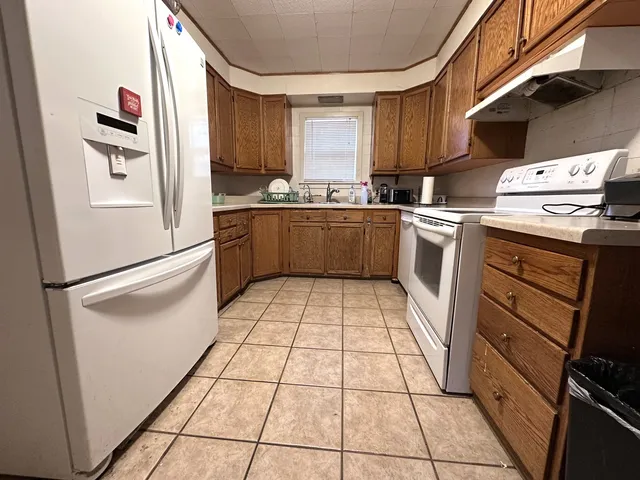 a kitchen with granite countertop a refrigerator and a stove top oven
