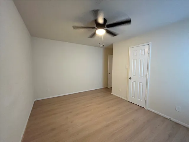 an empty room with ceiling fan and window