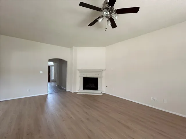 a view of an empty room with wooden floor and a fireplace