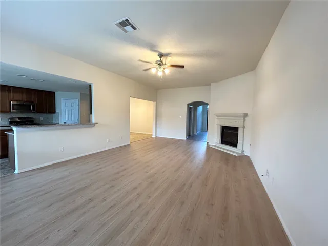 a view of empty room with wooden floor and fan