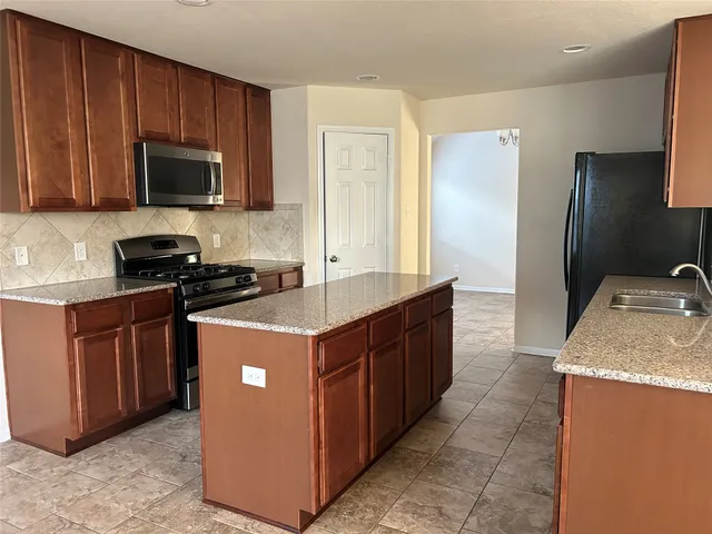 a kitchen with stainless steel appliances granite countertop a stove a sink and a refrigerator