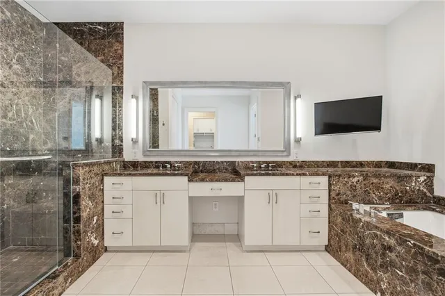 a bathroom with a granite countertop sink a mirror and shower