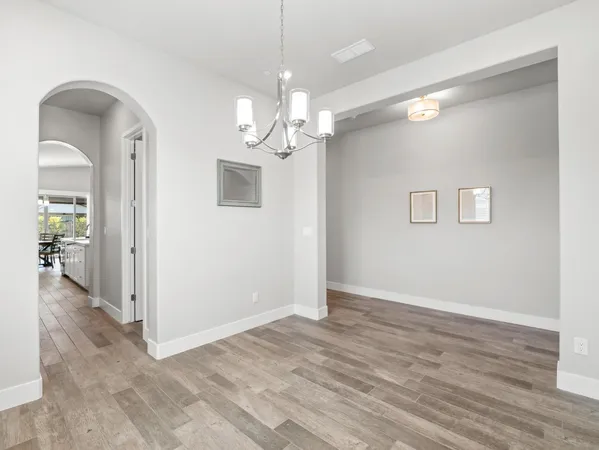 a view of a hallway with wooden floor and a chandelier