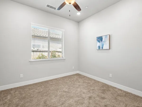 an empty room with window and ceiling fan