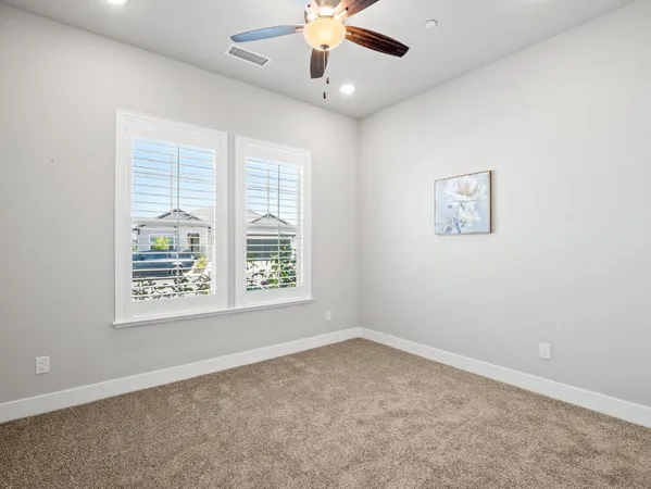 an empty room with a window and a ceiling fan