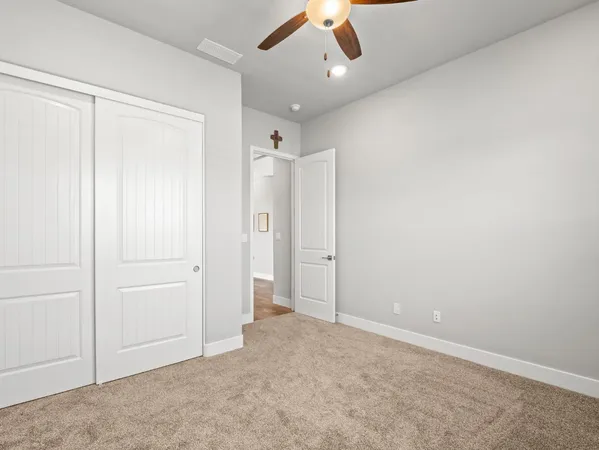an empty room with closet and a ceiling fan