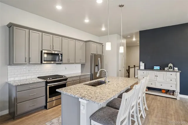 a kitchen with stainless steel appliances a kitchen island hardwood floor and a sink