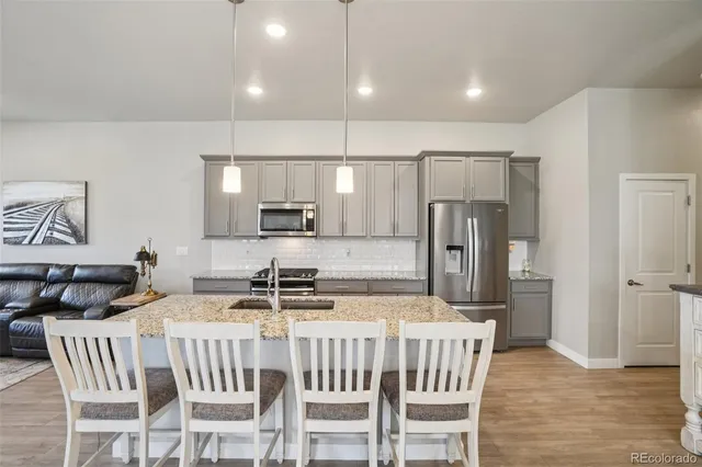 a kitchen with stainless steel appliances a refrigerator a stove a sink a dining table and chairs