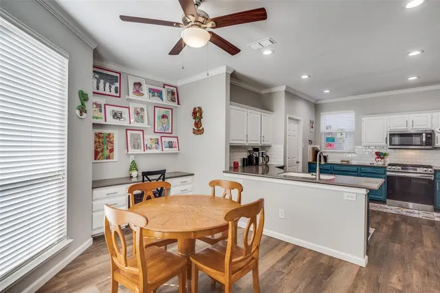 a kitchen with stainless steel appliances granite countertop a dining table chairs refrigerator and sink