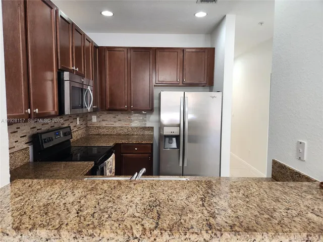 a kitchen with granite countertop wooden cabinets and stainless steel appliances