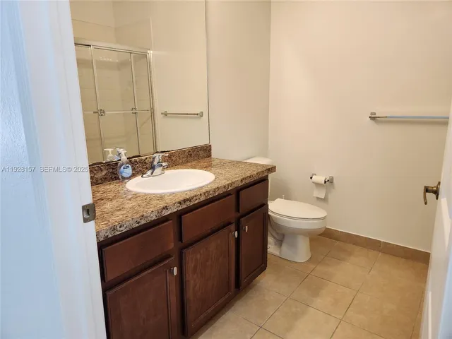 a bathroom with a granite countertop sink a toilet and a mirror
