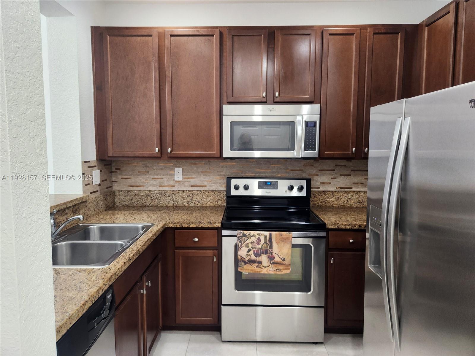 14677 Southwest 9th Street, Unit 1802 Pembroke Pines, FL 33027 - Photo 17 of 18 a kitchen with granite countertop wooden cabinets and stainless steel appliances