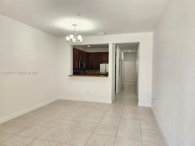 an empty room with kitchen and chandelier