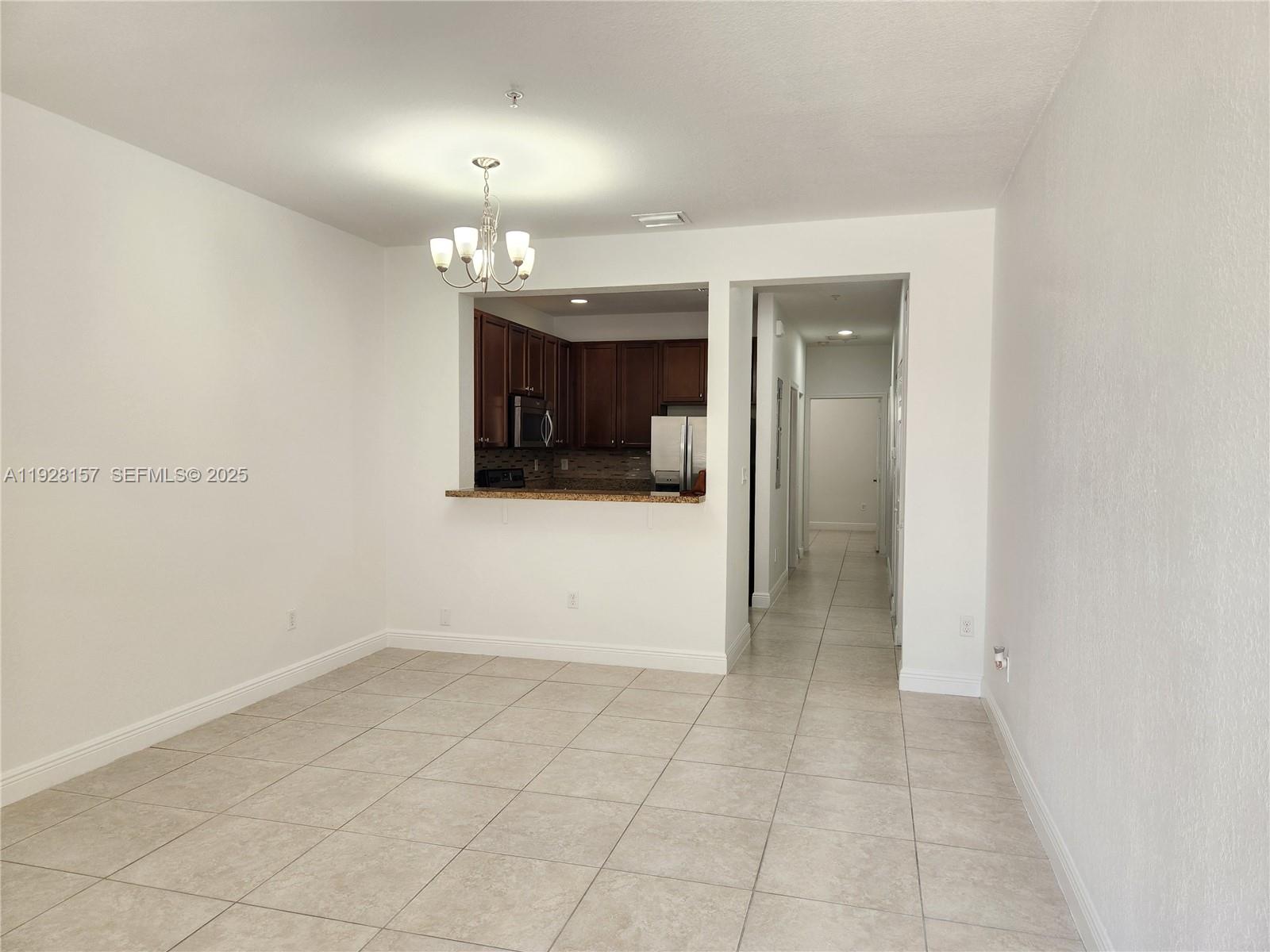 14677 Southwest 9th Street, Unit 1802 Pembroke Pines, FL 33027 - Photo 6 of 18 an empty room with kitchen and chandelier