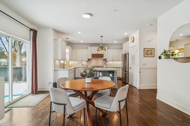 a dining room with stainless steel appliances kitchen island granite countertop a dining table chairs and a refrigerator