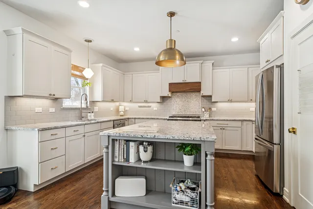 a kitchen with stainless steel appliances granite countertop a sink a stove a refrigerator and island with wooden floor