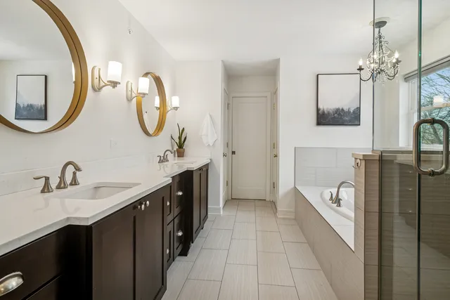 a en suite bathroom with a double vanity sink a mirror and a bathtub