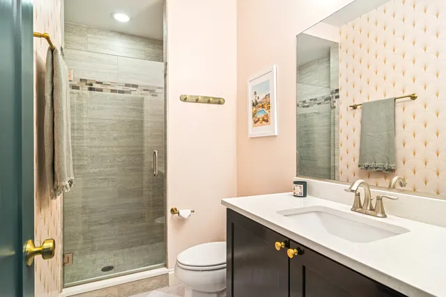 a bathroom with a shower sink vanity mirror and toilet