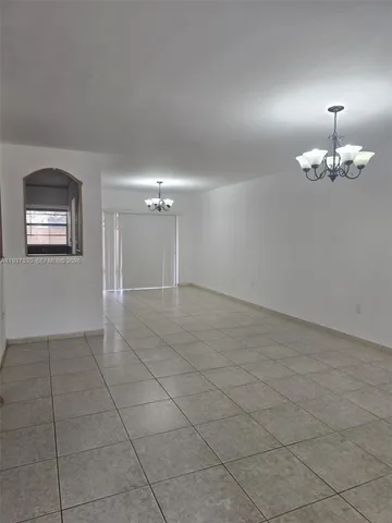 an empty room with chandelier fan and window