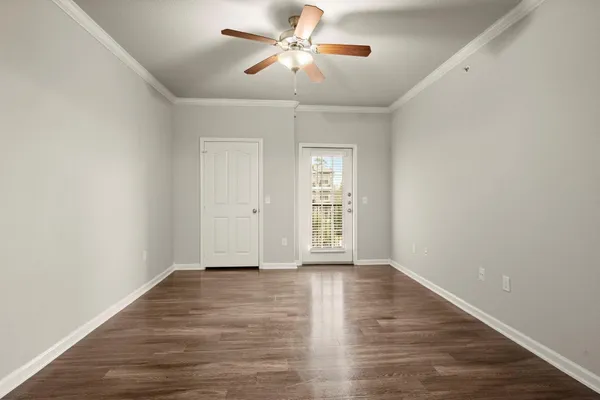 a view of an empty room with window and wooden floor