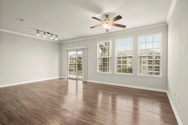 a view of an empty room with a window and wooden floor