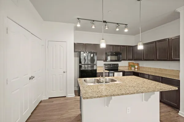 a kitchen with kitchen island a large counter top space stainless steel appliances and cabinets