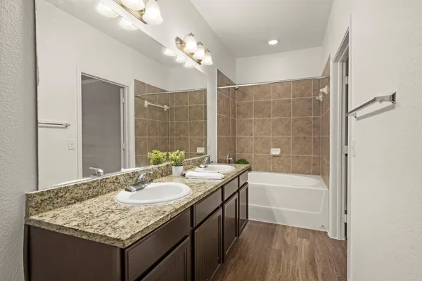a bathroom with a granite countertop sink a toilet a mirror and bathtub