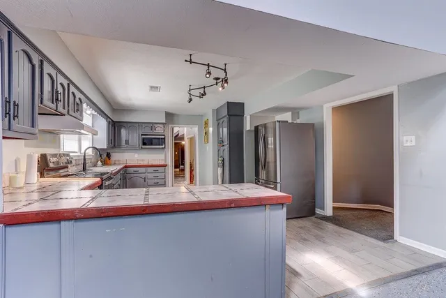a kitchen with stainless steel appliances granite countertop a sink refrigerator and cabinets