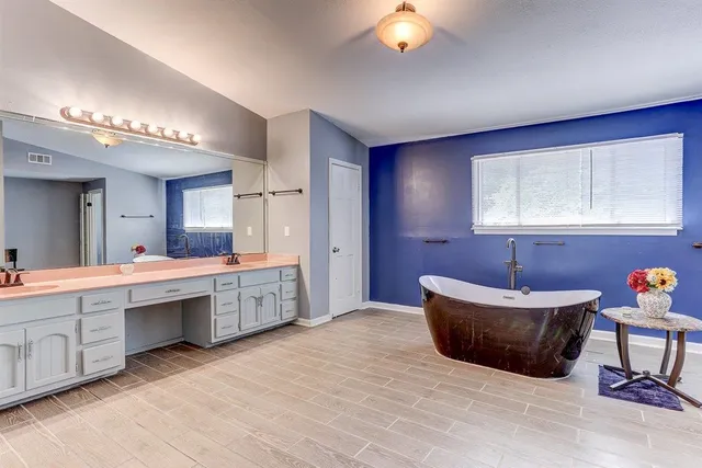 a spacious bathroom with a double vanity sink mirror and bathtub